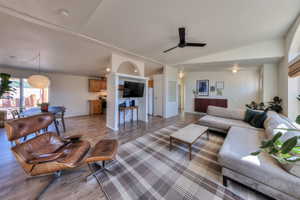 Living room featuring ceiling fan, lofted ceiling, and light wood-type flooring