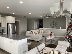 Interior space featuring a center island, ceiling fan with notable chandelier, appliances with stainless steel finishes, dark hardwood / wood-style flooring, and white cabinetry