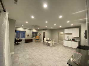 Interior space featuring ceiling fan, decorative backsplash, white cabinetry, and sink