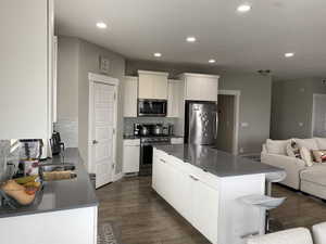 Kitchen featuring a center island, white cabinets, decorative backsplash, dark hardwood / wood-style floors, and stainless steel appliances