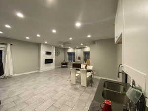 Kitchen featuring a breakfast bar, sink, ceiling fan, a large fireplace, and white cabinetry