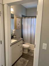 Full bathroom with shower / bath combo with shower curtain, vanity, hardwood / wood-style floors, and toilet