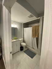 Bathroom with tile patterned flooring, a shower with curtain, vanity, and toilet