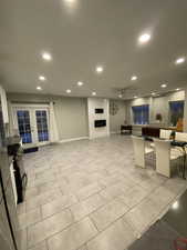 Living room with a large fireplace, ceiling fan, french doors, and light tile patterned floors