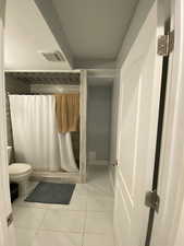 Bathroom featuring tile patterned floors, toilet, and a shower with shower curtain