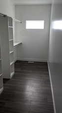 Walk in closet with dark hardwood / wood-style floors