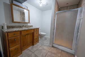 Bathroom featuring tile patterned floors, vanity, toilet, and a shower with shower door