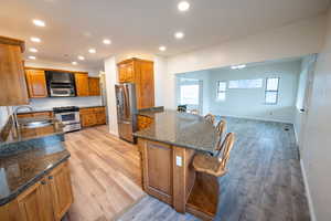 Kitchen featuring a kitchen bar, sink, dark stone counters, and stainless steel appliances