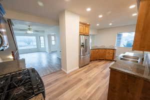 Kitchen with sink, light wood-type flooring, stainless steel refrigerator with ice dispenser, and a wealth of natural light