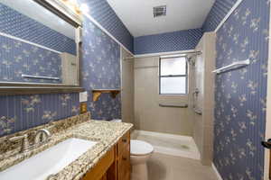 Bathroom with a tile shower, tile patterned flooring, a textured ceiling, toilet, and vanity