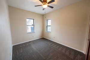 Unfurnished bedroom with dark colored carpet and ceiling fan