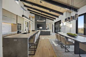 Kitchen featuring tasteful backsplash, wood ceiling, a kitchen island with sink, beam ceiling, and decorative light fixtures