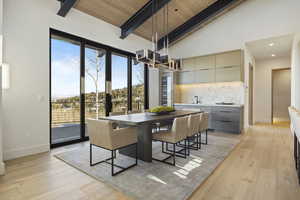 Dining room with light hardwood / wood-style floors, beam ceiling, wooden ceiling, and sink