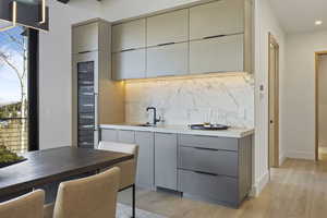 Kitchen featuring gray cabinetry, light wood-type flooring, sink, and tasteful backsplash