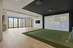 Interior space with beam ceiling, wood-type flooring, and golf simulator