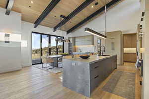 Kitchen featuring gray cabinetry, sink, hanging light fixtures, high vaulted ceiling, and a spacious island