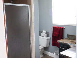 Bathroom with tile patterned flooring, vanity, a shower with shower door, and toilet