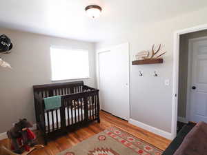 Bedroom with a closet, a crib, and hardwood / wood-style flooring