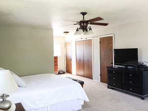 Bedroom featuring a textured ceiling, light colored carpet, and ceiling fan