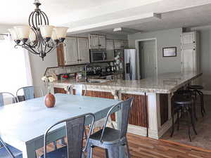 Kitchen with sink, hanging light fixtures, an inviting chandelier, a textured ceiling, and appliances with stainless steel finishes