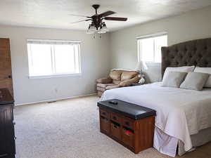 Carpeted bedroom with ceiling fan and a textured ceiling