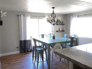 Dining area featuring plenty of natural light, dark hardwood / wood-style floors, a textured ceiling, and a chandelier