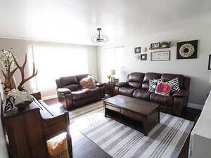 Living room with a notable chandelier, a healthy amount of sunlight, and wood-type flooring