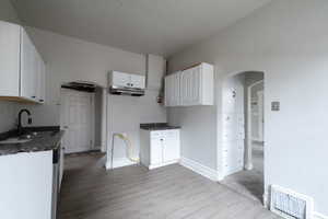 Kitchen with light lvp flooring, white cabinetry, and sink