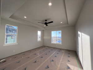 Empty room featuring ceiling fan and a raised ceiling