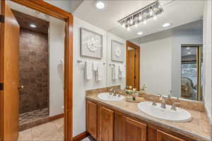 Bathroom featuring a tile shower, tile patterned flooring, vanity, and toilet