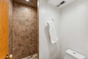 Bathroom featuring tiled shower and toilet