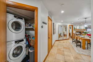 Laundry area featuring stacked washer / drying machine and light tile patterned flooring