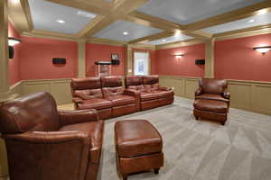 Home theater featuring light carpet, beamed ceiling, coffered ceiling, and ornamental molding