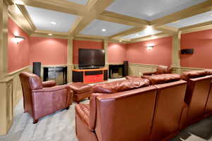 Carpeted home theater room featuring beam ceiling, crown molding, and coffered ceiling