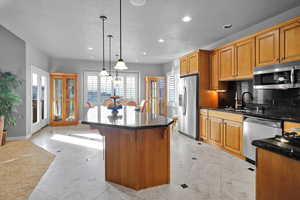 Kitchen with backsplash, sink, a breakfast bar area, decorative light fixtures, and stainless steel appliances