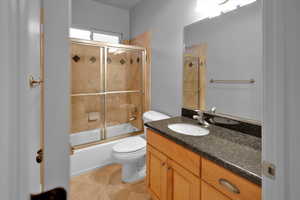 Full bathroom with tile patterned flooring, vanity, toilet, and enclosed tub / shower combo