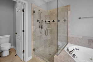 Bathroom with tile patterned floors, separate shower and tub, and toilet