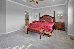 Bedroom featuring ceiling fan, light colored carpet, ornamental molding, and connected bathroom