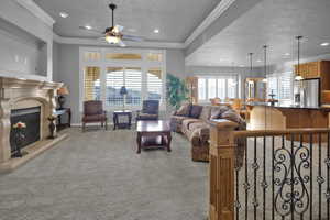 Carpeted living room featuring a textured ceiling, ceiling fan, and crown molding