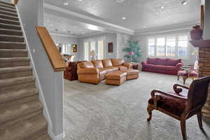 Carpeted living room featuring a textured ceiling and crown molding