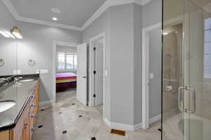 Bathroom with tile patterned floors, vanity, a shower with door, and crown molding