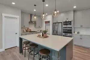 Kitchen with gray cabinetry, a kitchen island, wall chimney range hood, and appliances with stainless steel finishes