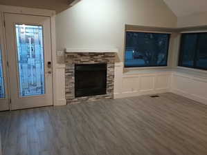 Unfurnished living room with a stone fireplace and light wood-type flooring