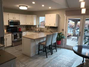 Kitchen featuring pendant lighting, sink, white cabinets, and stainless steel appliances