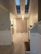 Hall with light wood-type flooring and high vaulted ceiling