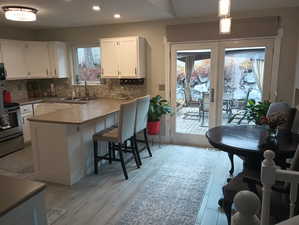 Kitchen featuring a kitchen bar, pendant lighting, and white cabinetry