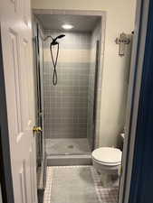 Bathroom with tile patterned floors, toilet, and walk in shower