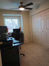 Home office with ceiling fan and light colored carpet