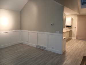 Empty room with light hardwood / wood-style floors and lofted ceiling