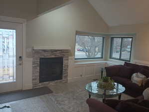 Living room featuring plenty of natural light, a stone fireplace, and high vaulted ceiling